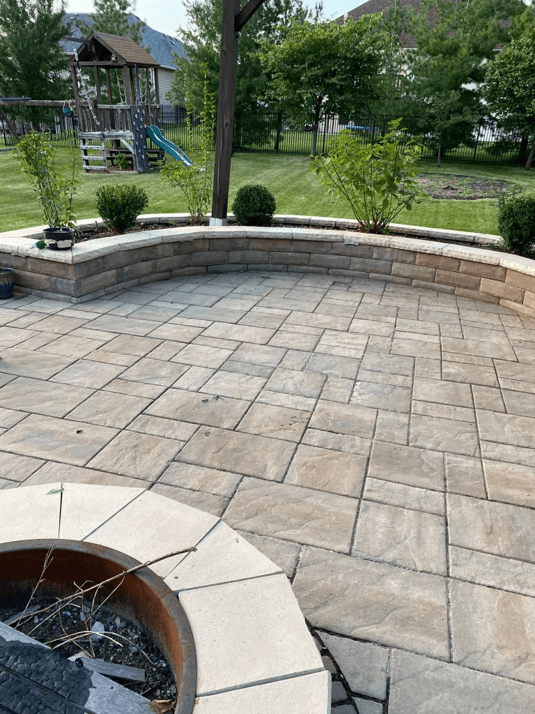 Custom stone paver patio with curved retaining wall and built-in fire pit